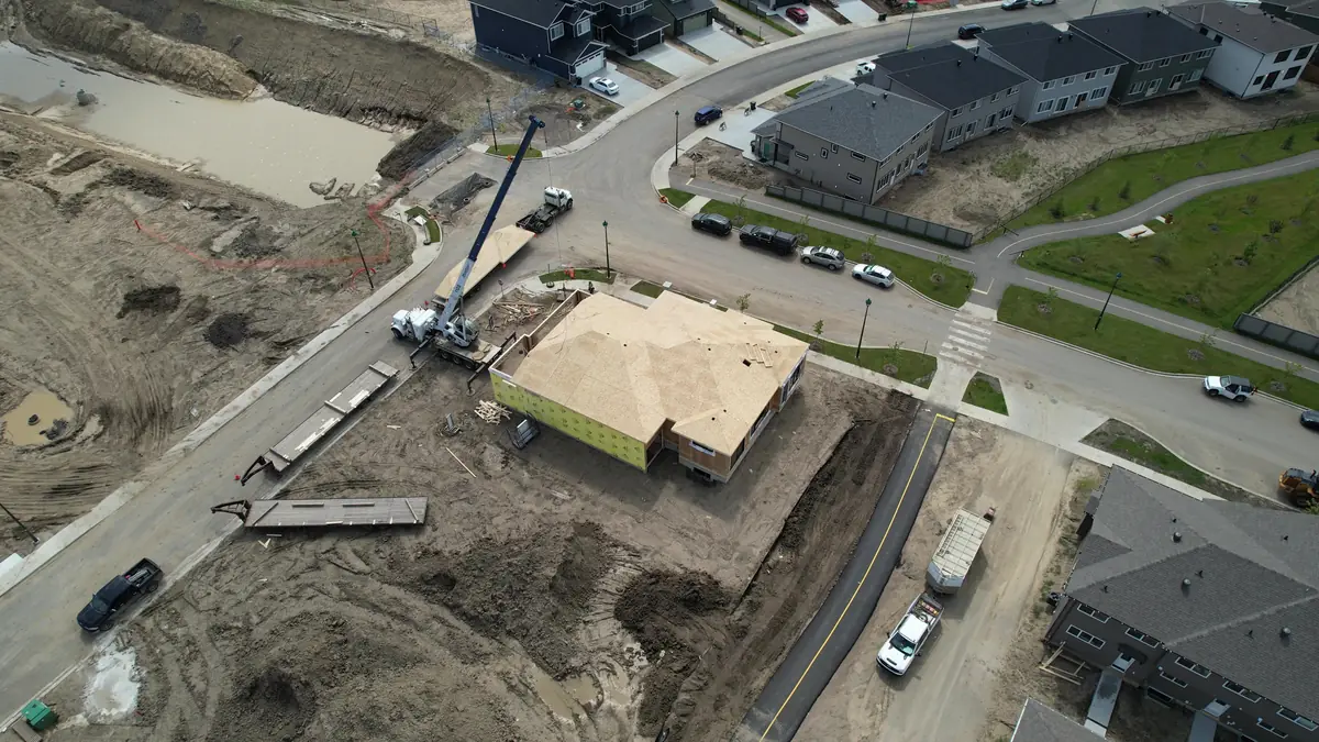 A crane sets roof panels on a new ACQBuilt home