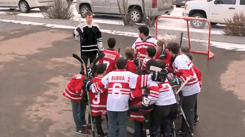 Kids in red jerseys playing street hockey