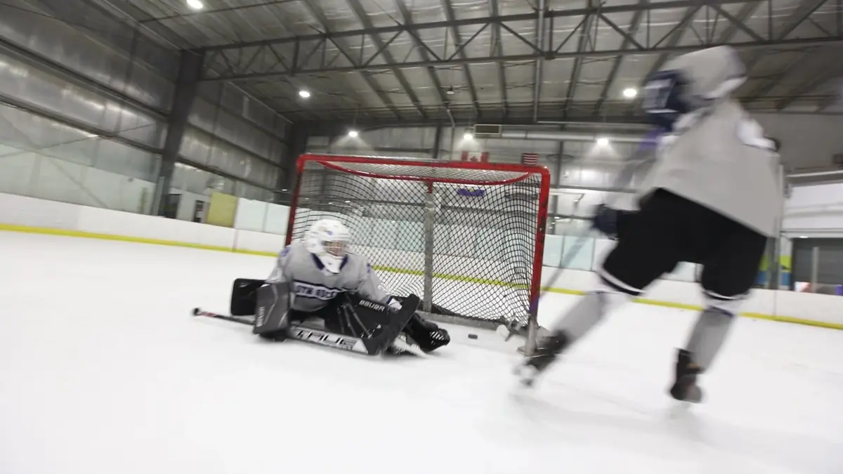 A goalie stretches across the crease at a St. Thomas More practice